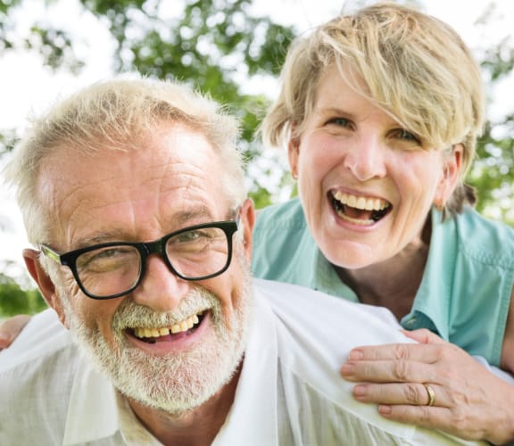 Middle aged man smiling and standing in front of a white wall